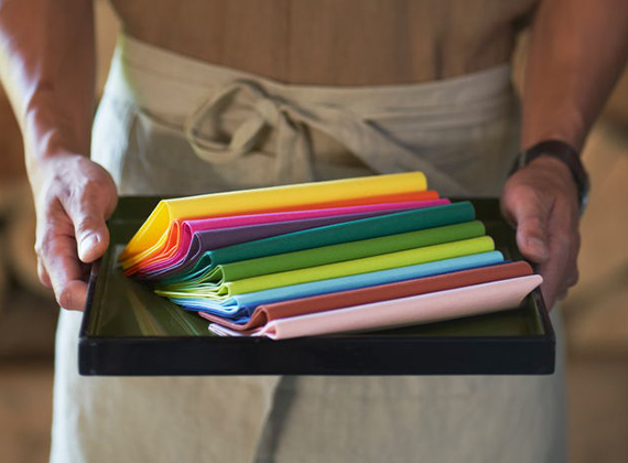 Colourful range of sustainable napkins held by waiter on a tray